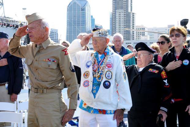 World War II veterans render a hand salute during the parading of the colors during a wreath ceremony held aboard the USS Midway Museum. (U.S. Navy/Nolan Kahn)