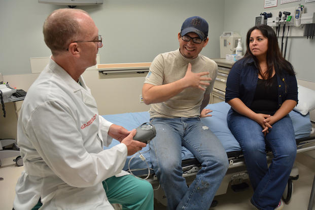Army Col. Evan Renz explains the function of a vacuum-assisted closure device to Indalecio Morales while Morales' wife, Maribel, looks on in the U.S. Army Institute of Surgical Research Burn Center at San Antonio Military Medical Center. (U.S. Army/Lori Newman)