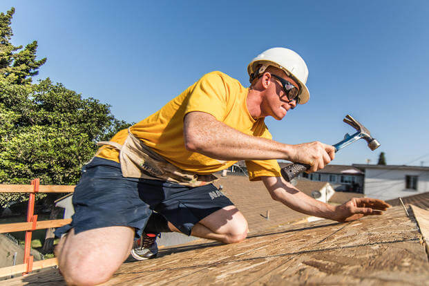 Boatswain's mate Zach Lee, USS Anchorage (LPD 23), hammers nails into the roof of a house during a Habitat for Humanity neighborhood rebuild project in Long Beach, California, during Los Angeles Fleet Week.