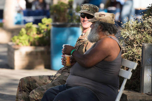 Two veterans sit on a bench. 