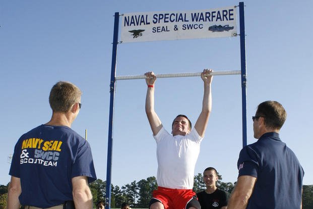 A high school student tries to do a pull-up during a Navy SEAL Fitness Challenge.