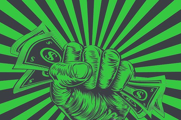 fist holds dollars against green and black background