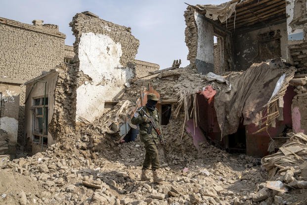 A Taliban fighter checks a destroyed Islamic State group house