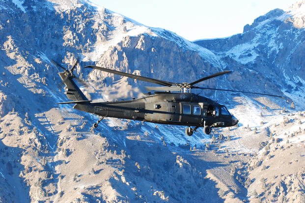 A 10th Combat Aviation Brigade UH-60 Black Hawk helicopter passes a snow-covered mountain in eastern Afghanistan during a personnel movement flight.