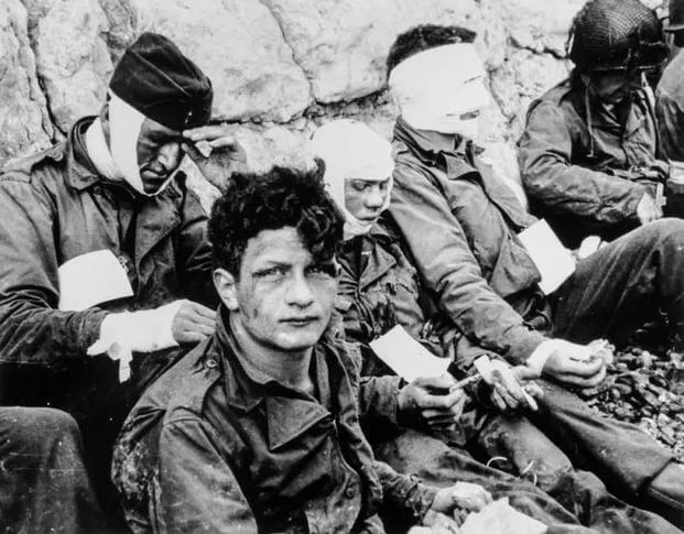 A group of American assault troops who, although wounded, stormed the beachhead and gained the comparative safety of the chalk cliffs at their backs. (Photo courtesy of the National Archives and Records Administration) A group of American assault troops who, although wounded, stormed the beachhead and gained the comparative safety of the chalk cliffs at their backs. (Photo courtesy of the National Archives and Records Administration)