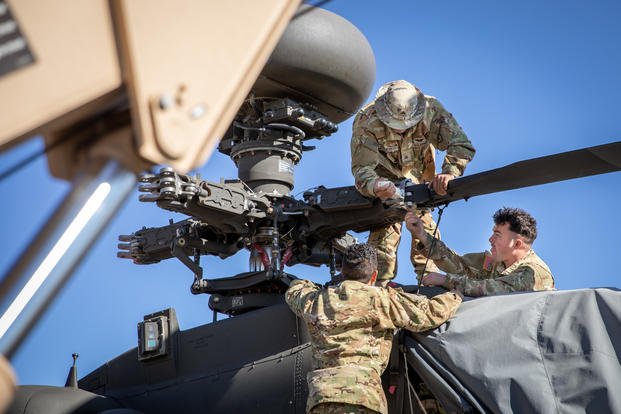 Staff Sgt. Jorge Pacheco, Sgt. Santiago Figuereo, and Spc. Jacob Stokes, AH-64 attack helicopter repairers assigned to the 2-6 Cavalry Regiment, 25th Combat Aviation Brigade, position a blade for a strappack replacement on the main rotor head of an AH-64 Apache Attack Helicopter at Pohakuloa Training Area (PTA), Hawai’i, Hawai’i, August 1, 2025. Before each flight, the main rotorhead is inspected for cracks and if any are found, the blades need to be taken off so the damaged parts can be replaced. (U.S. Army Photo by Sgt. Olivia Cowart)