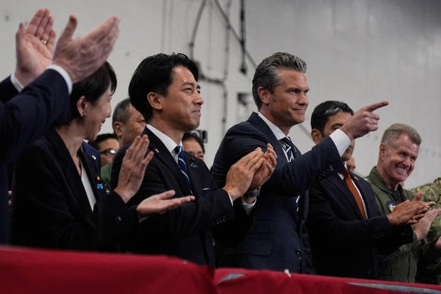 U.S. Defense Secretary Pete Hegseth, center right, with Japanese Prime Minister Sanae Takaichi, left, and Defense Minister Shinjiro Koizumi, gestures as they listen to President Donald Trump speak to members of the military aboard the USS George Washington, an aircraft carrier docked at an American naval base, in Yokosuka, south of Tokyo, Tuesday, Oct. 28, 2025. (AP Photo/Mark Schiefelbein) Japan Trump Asia