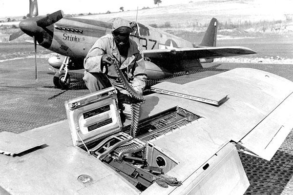An armorer inspects ammunition in a red-tailed P-51’s 50-cal. machine guns. (U.S. Air Force photo)