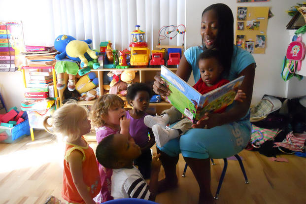 LaQuanda Alston, a childcare provider, reads a storybook to military children in her care at her home. (Photo: Rita C. Hall/U.S. Army.)