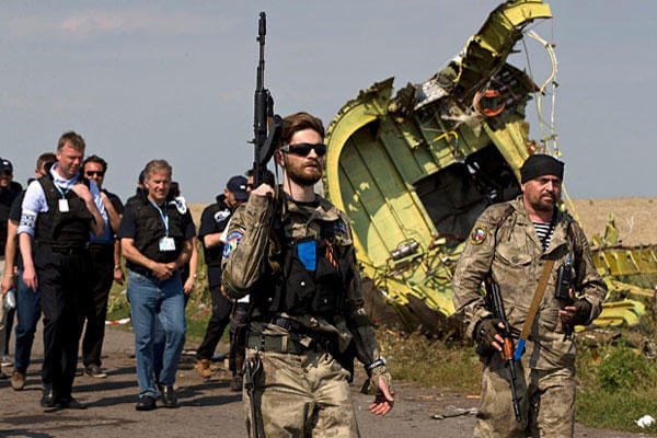 Pro-Russian rebels, followed by members of the OSCE mission, walk by plane wreckage as they arrive for a media briefing at the crash site of Malaysia Airlines Flight 17, near the village of Hrabove, eastern Ukraine, on July 22. (AP Photo/Vadim Ghirda)