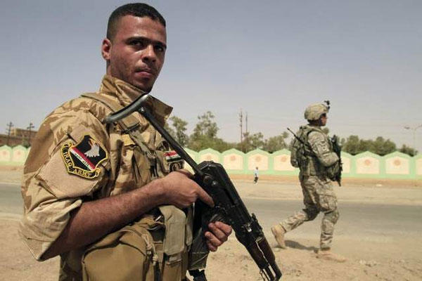 An armed Sunni militiaman wearing an Iraqi Army patch, left, and a U.S. Army soldier patrol in Samarra on Oct. 6, 2010. (Maya Alleruzzo / AP file)