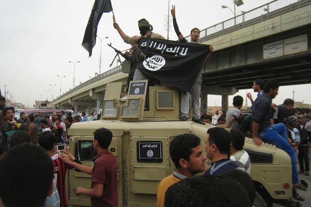 Islamic State group militants wave al-Qaida flags as they patrol in a commandeered Iraqi military vehicle in Fallujah, 40 miles (65 kilometers) west of Baghdad, Iraq. (AP Photo, File)