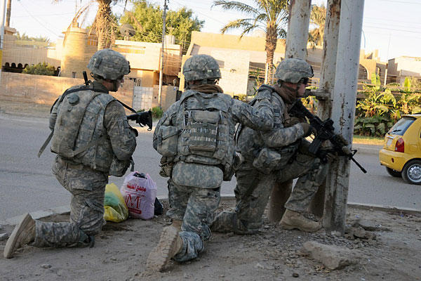 U.S. troops take a knee at a street corner before continuing a patrol in Baghdad in this file photo from Oct. 23, 2011. John Laughter/Army