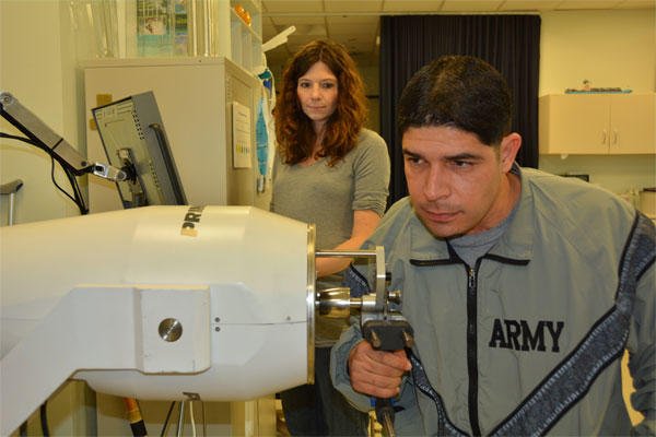 Army 1st Lt. John Arroyo works on strengthening his right hand while his occupational therapist, Katie Korp, looks on at the Center for the Intrepid, Brooke Army Medical Center’s rehabilitation facility, Jan. 16, 2015. (U.S. Army photo/Robert Shield)