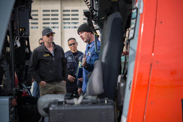 A Coast Guard member explains the features of a MH-65 Dolphin helicopter to K-9 teams at Coast Guard Air Station San Francisco, Wednesday, Dec. 2, 2015, to prepare for Super Bowl 50. (Photo: Petty Officer 3rd Class Loumania Stewart)