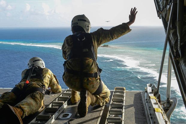 Australian Army Cpl. Teome Matamua and Sgt. Phillip McIllvaney wave to islanders in the Federated States of Micronesia after delivering donated goods and critical supplies during Operation Christmas Drop. (Photo: Staff Sgt. Katrina Brisbin)