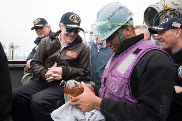 Secretary of the Navy Ray Mabus receives a fuel sample of alternative fuel from Gas Turbine Systems Technician (Mechanical) 3rd Class Shalen Shivers. (Photo: Mass Communication Specialist 2nd Class Armando Gonzales)