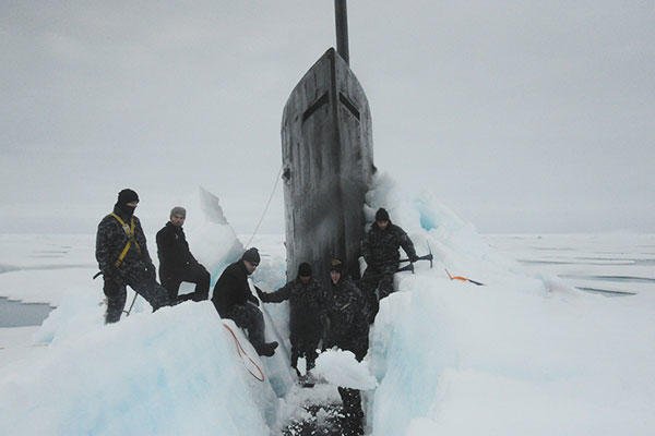 Sailors aboard the fast attack submarine USS Seawolf (SSN 21) remove Arctic ice from the hull after surfacing at the North Pole. (U.S. Navy)