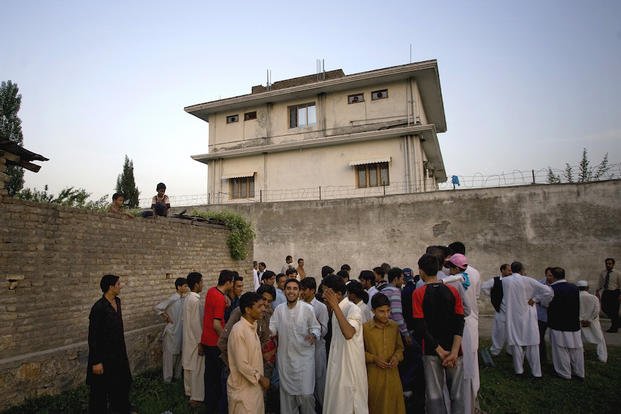 In this May 3, 2011 file photo, local residents gather outside a house, where al-Qaida leader Osama bin Laden was caught and killed in Abbottabad, Pakistan. 