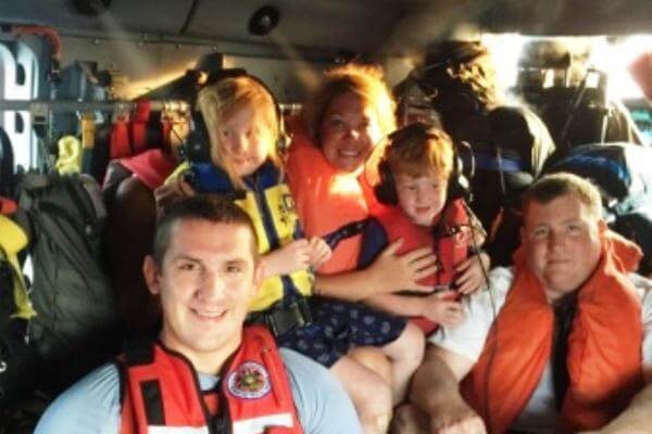 A rescue swimmer from Coast Guard Air Station Elizabeth City, N.J., poses with passengers aboard an MH-60 Jayhawk helicopter Monday, July 20, 2015. The crew hoisted six passengers after their boat ran aground in Wachapreague, Va. (US Coast Guard photo)