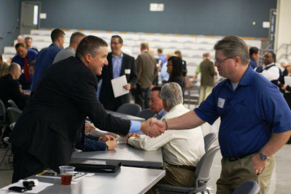 Steve Nolen, chief of planning and environmental division, shakes hands with a business representative during the Meet the Corps Day event.