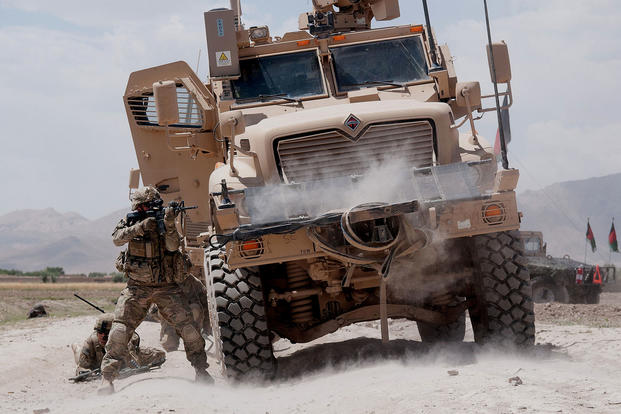 A U.S. Army paratrooper fires his M4 carbine at insurgents during a firefight in June 2012, in Ghazni Province, Afghanistan, using a Mine Resistant Ambush Protected vehicle for cover. (US Army photo/Michael MacLeod)