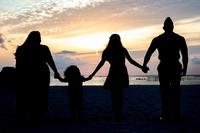 Silhouette of a military family walking on the beach.