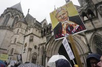 Protesters stand with posters at the Royal Courts of Justice entrance