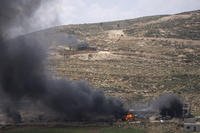 Israeli settlers gather near burning properties of Palestinian villagers.