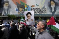 Iranian worshippers walk past a mural.