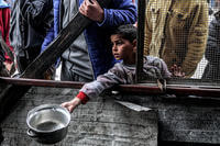 A boy holds out an empty pot as he waits with other displaced Palestinians queueing for meals, provided by a charity organization ahead of the fast-breaking ‘iftar’ meal during the Muslim holy month of Ramadan, in Rafah in the southern Gaza Strip.