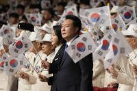South Korean President Yoon Suk Yeol, center right, and his wife Kim Keon Hee wave the national flags