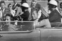 President John F. Kennedy waves from his car in a motorcade in Dallas.