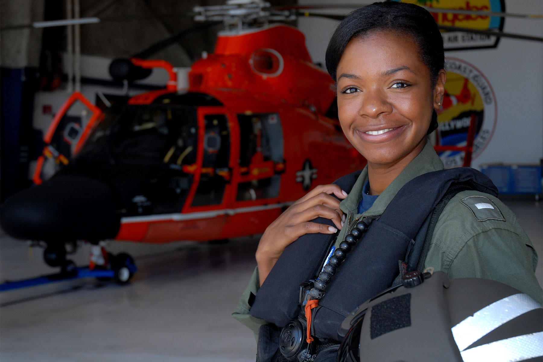 Lt. j.g. Lashanda Holmes stands in front of an MH-65 Dolphin helicopter at Air Station Los Angeles. (U.S. Coast Guard/ Adam Eggers)