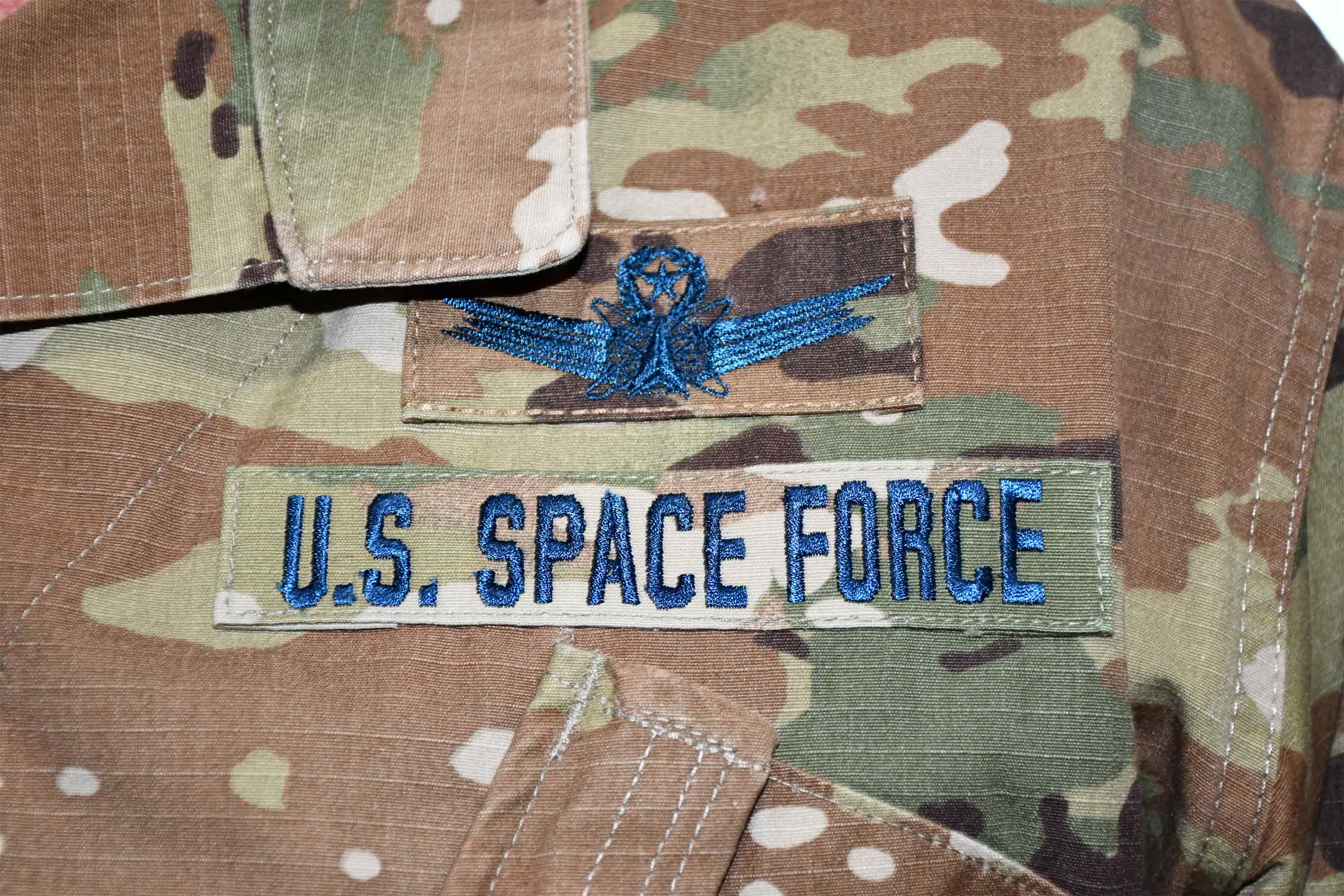 Airmen who transfer into the U.S. Space Force will continue to wear the OCP utility uniform, but with blue thread and a colored U.S. flag.