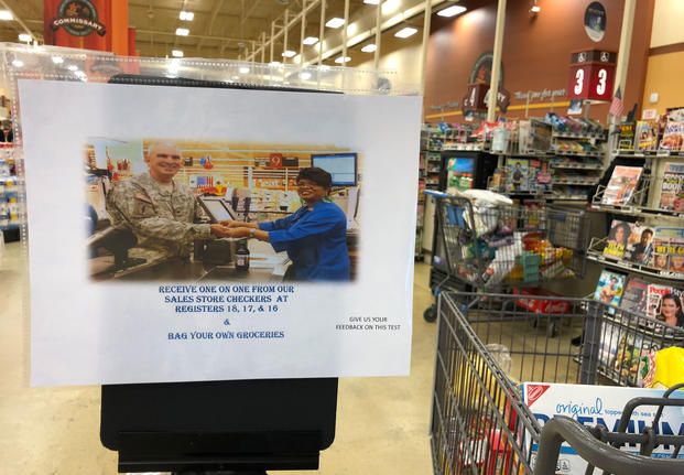A sign at the Anchorage, Alaska area commissary notifies customers that certain lanes no longer offering bagging services. (Photo: Military.com)