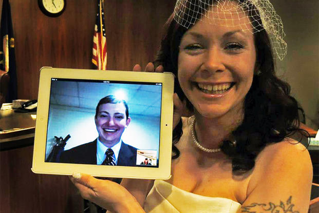 Kari Phelps, spouse of Senior Airman Daniel Phelps, 39th Air Base Wing Public Affairs photojournalist, holds a digital screen of her husband during their online wedding ceremony Oct. 29, 2012. (Courtesy photo)