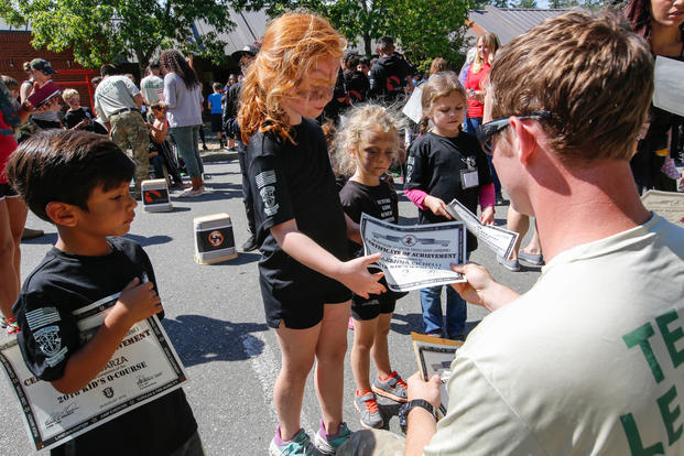A child of a 1st Special Forces Group (Airborne) Soldier receives her honorary Green Beret certificate during the 10th Annual Kid’s Q-Course. (U.S. Army/Ian Ives)