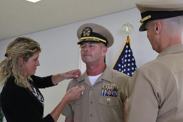 Cmdr. David Dwyer, deputy commander of U.S. Naval Ship Repair Facility and Japan Regional Maintenance Center (SRF-JRMC), is pinned to the rank of captain by his wife, left, and Capt. Garrett Farman, right, the commanding officer. (U.S. Navy photo/Joyce Lopez)