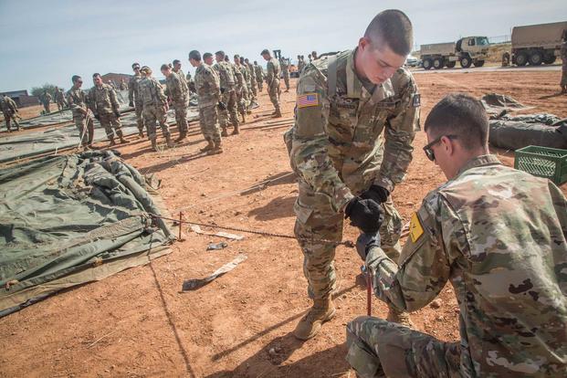 U.S. Army soldiers, assigned to 309th Military Intelligence Battalion and 305th Military Intelligence Battalion, work together to hammer a stake into the ground to keep a tent stable at Fort Huachuca, Arizona, on Nov. 1, 2018, as they build a "Tent City" to house troops for Operation Faithful Patriot. (U.S. Army photo by Spc. Brandon Best)