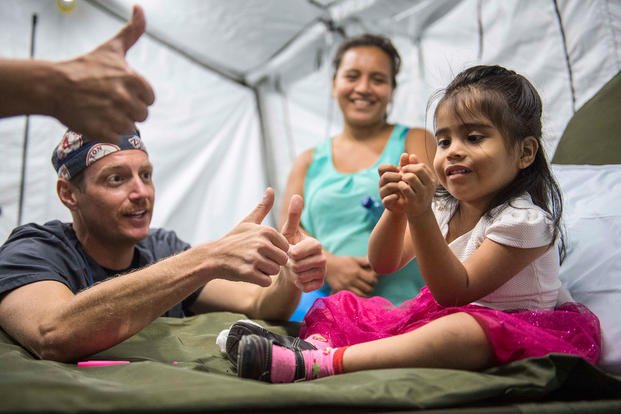 Navy Lt. Cmdr. Jason Souza encourages a girl to give a thumbs up after a finger surgery in Puerto Barrios, Guatemala, April 16, 2018, during the Continuing Promise 2018 training mission. (U.S. Navy photo by Petty Officer 2nd Class Brianna K. Green)