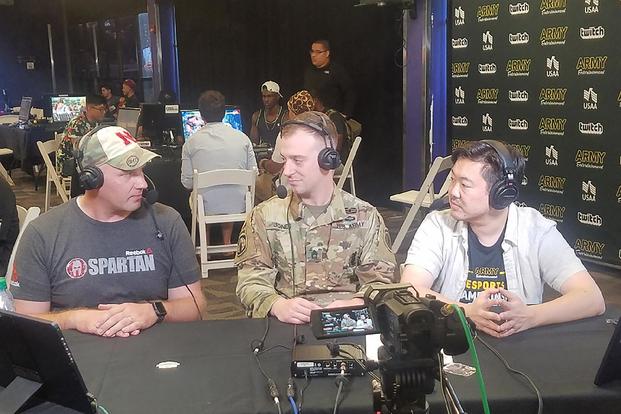 Capt. Ryan Lewis talks to Sgt. 1st Class Christopher Jones and @twitch.tv shout caster James “jchensor” Chen during the Army Entertainment Esports Street Fighter V tournament 11 August 2018, at the Alternate Escapes Café at Fort Gordon, Georgia. (U.S. Army 2nd Recruiting Brigade)