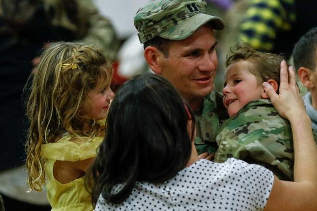 A captain assigned to 2nd Infantry Brigade Combat Team, 4th Infantry Division, embraces his children at a welcome home ceremony at the William "Bill" Reed Special Events Center at Fort Carson, Colorado., on Nov. 18, 2018. The Army is instituting a number of changes to ease child care, spouse employment and PCS issues. (U.S. Army photo by Capt. Daniel Parker)