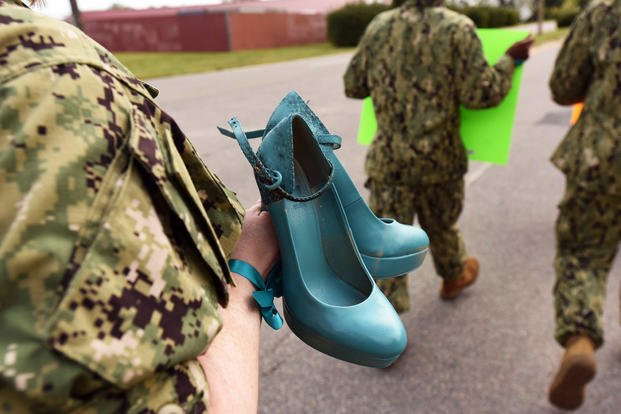 A sailor from Navy Expeditionary Combat Command carries a pair of shoes, painted teal to symbolize victims of sexual assault, as she participates in a “Walk a Mile in Their Shoes” command event on board Joint Expeditionary Base Little Creek, April 25, 2018. (U.S. Navy photo/Lisa Reese)