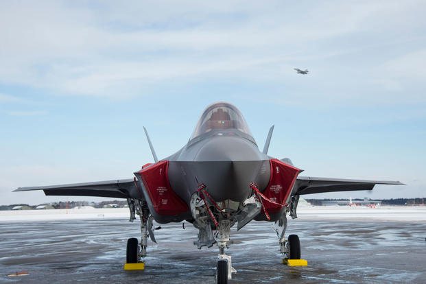 The first operational Japan Air Self-Defense Force F-35A sits on the flightline while an F-16 Fighting Falcon takes off during the F-35A’s arrival ceremony at Misawa Air Base, Japan, Jan. 25, 2018. (U.S. Air Force photo/Deana Heitzman)