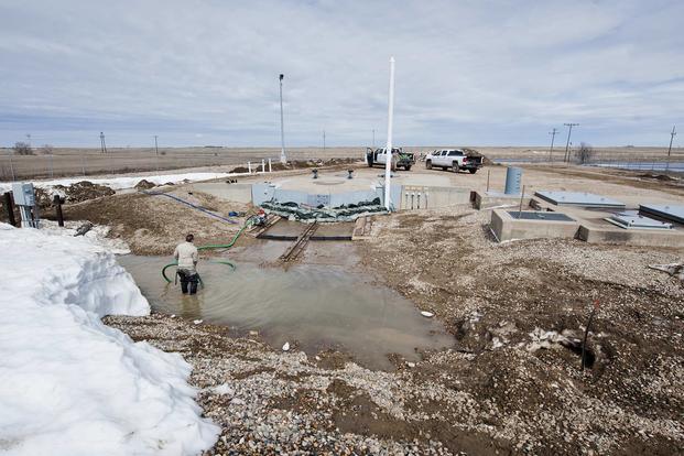 Airmen from the 91st Missile Maintenance Squadron drain flood-water from a launch facility near Bowbells, N.D., March 29, 2017. The electromechanical team technicians measured rising water levels and relocated water, snow and mud away from critical 91st MW assets. (U.S Air Force photo/Senior Airman J.T. Armstrong)