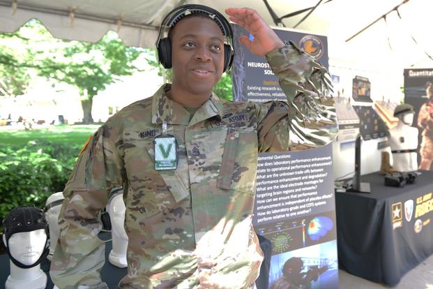 Staff Sgt. Christian King-Lincoln tries on a headset providing neurostimulation from a wireless transmitter behind him at Close Combat Lethality Tech Day, May 25, 2018. (U.s Army/Gary Sheftick)  