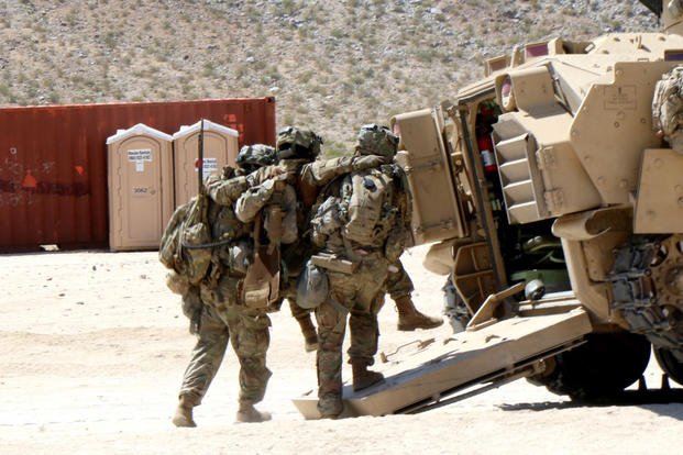 Two infantrymen from the 3rd Infantry Division’s 2nd Armored Brigade Combat Team carry an fellow soldier injured during a May 8 attack on the fictional town of Razish at the National Training Center at Fort Irwin, California. (Matthew Cox/Staff)