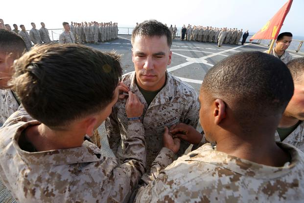 Cpl. Fabaino E. Tornberg, left, a machine gunner, and Sgt. Rodrigue Maxius, right, a rifleman, pins chevrons on Cpl. Gregory Opinski, a machine gunner, all with Kilo Company, Battalion Landing Team 3rd Battalion, 6th Marine Regiment, 24th Marine Expeditionary Unit, during his promotion to corporal aboard the dock landing ship USS Fort McHenry (LSD 43), on April 1, 2015. (U.S. Marine Corps photo by Sgt. Devin Nichols)