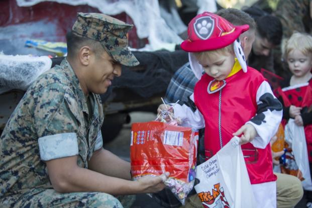A trick-or-treater gets candy from a Marine.